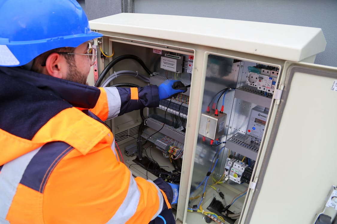 Electrician in hi-vis working on outdoor electrical panel in Strathcona County